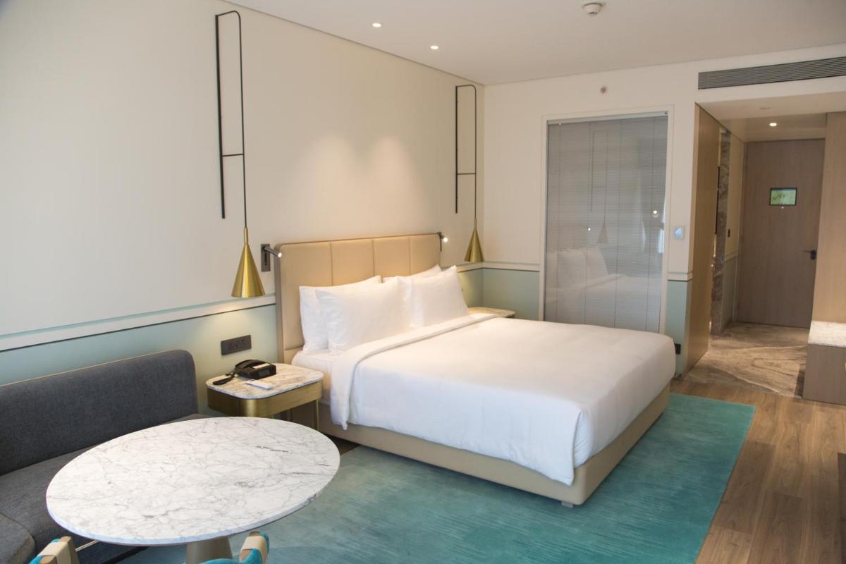 a hotel room with a bed and a table at Radisson Blu Mumbai International Airport in Mumbai a hotel room with a bed and a table at Radisson Blu Mumbai International Airport in Mumbai