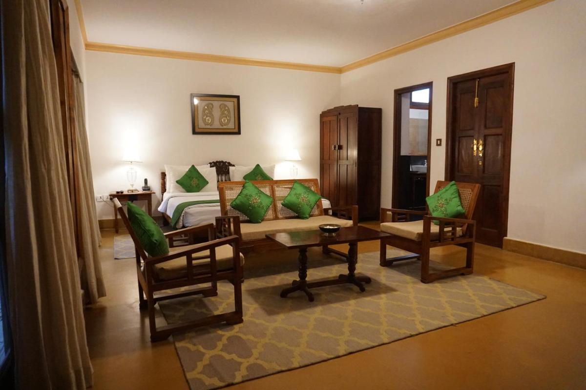 a bedroom with a bed and two chairs and a table at Saraca Hotel Lucknow in Lucknow