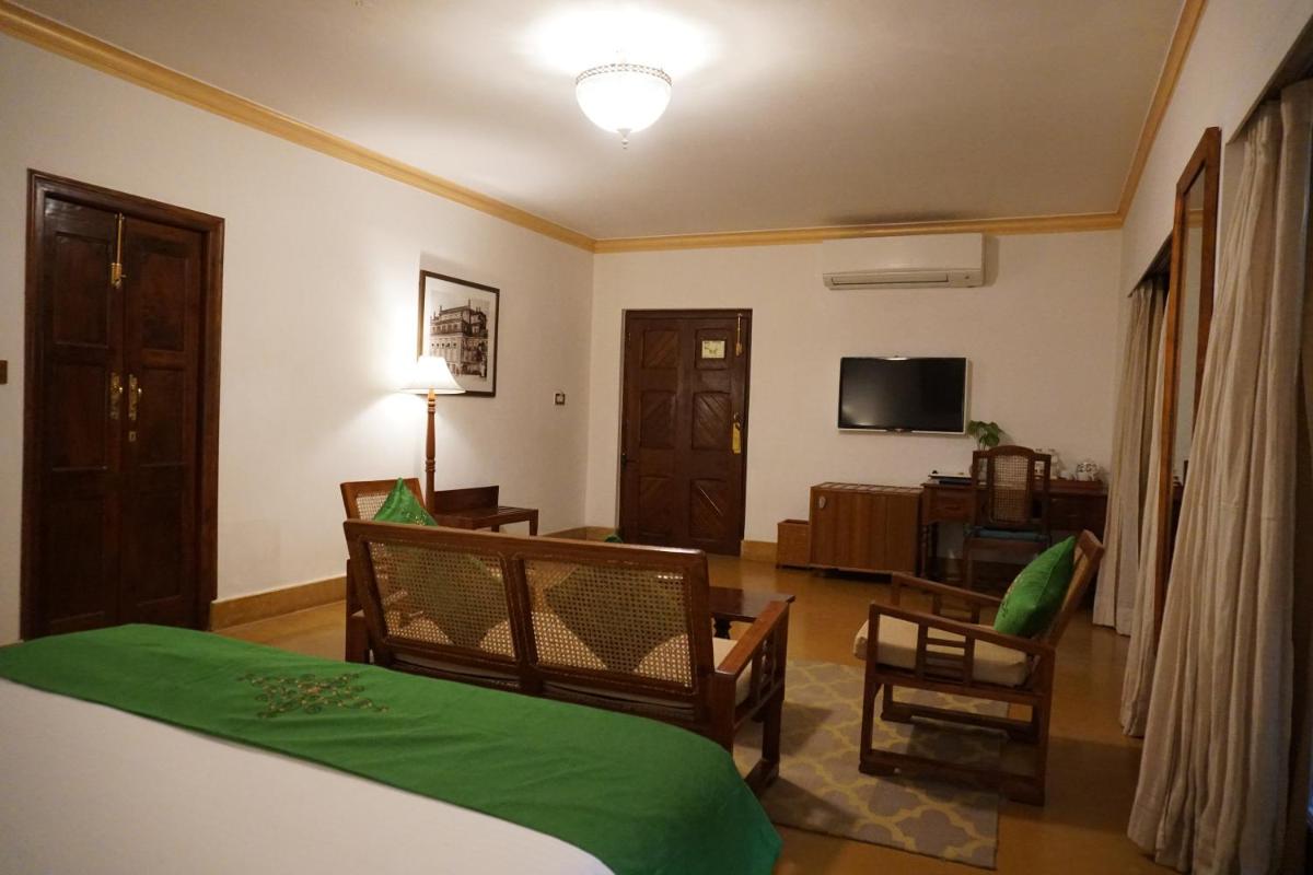a bedroom with a bed and a living room at Saraca Hotel Lucknow in Lucknow