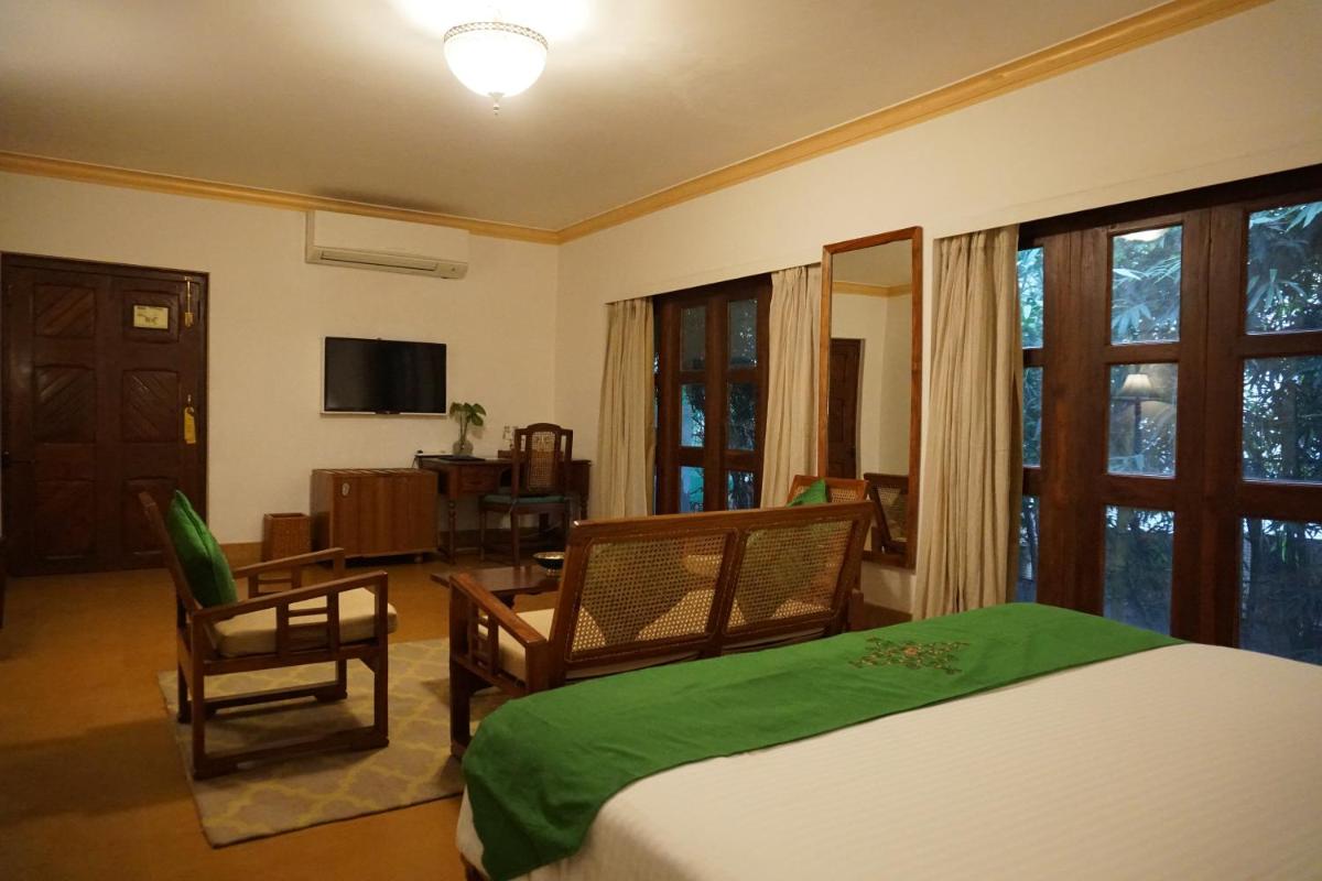 a bedroom with a bed and chairs and a television at Saraca Hotel Lucknow in Lucknow