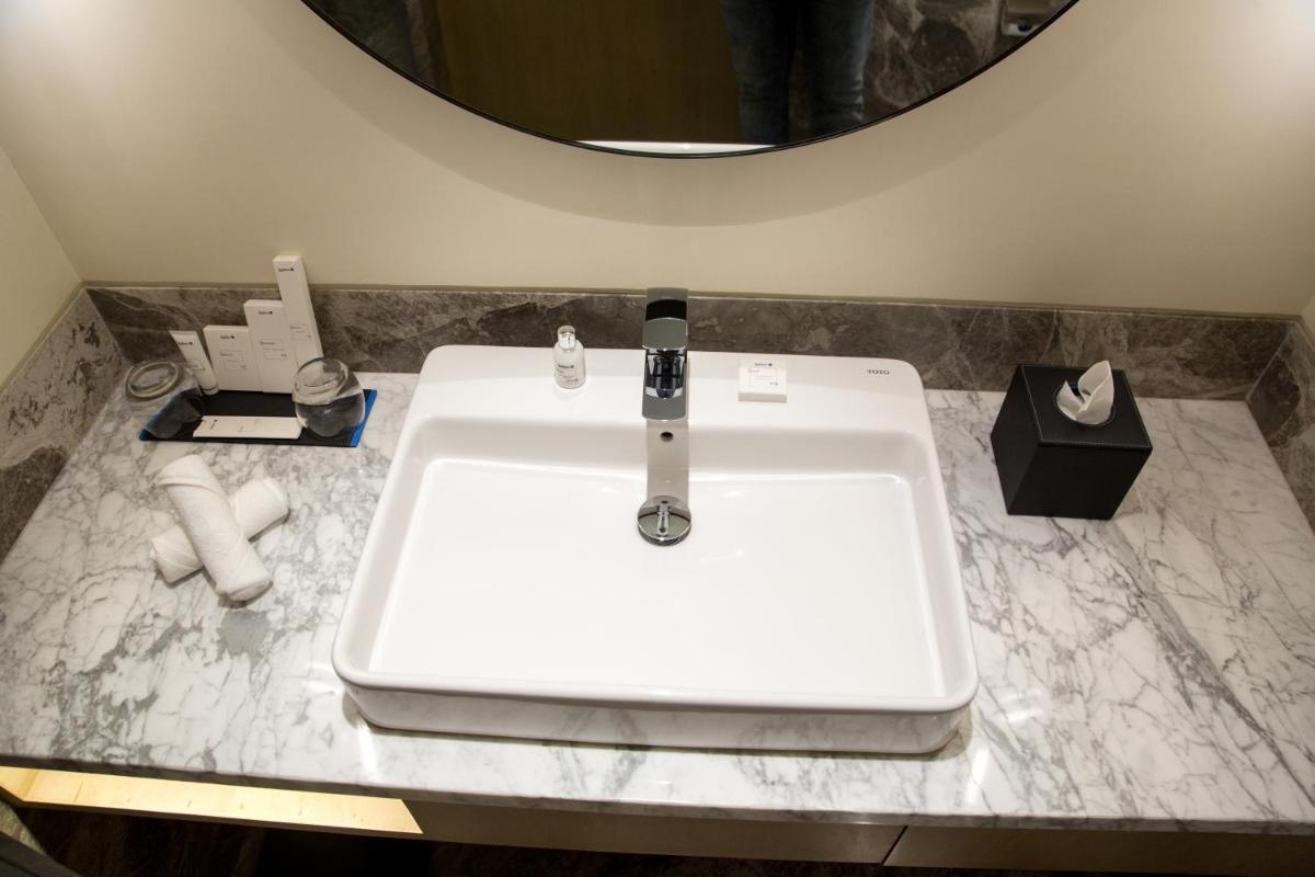 a bathroom with a white sink and a mirror at Radisson Blu Mumbai International Airport in Mumbai a bathroom with a white sink and a mirror at Radisson Blu Mumbai International Airport in Mumbai