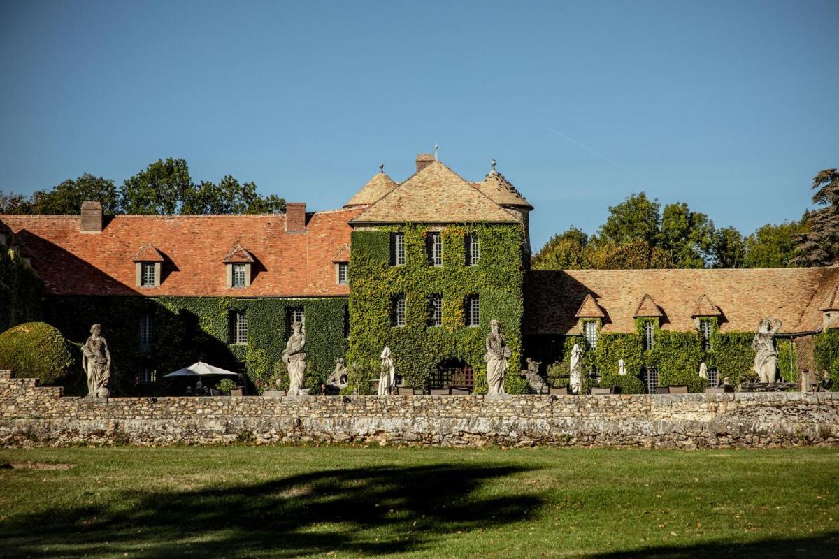 un grand bâtiment vert avec des statues devant dans l'établissement Château De Villiers-Le-Mahieu, à Villiers-le-Mahieu