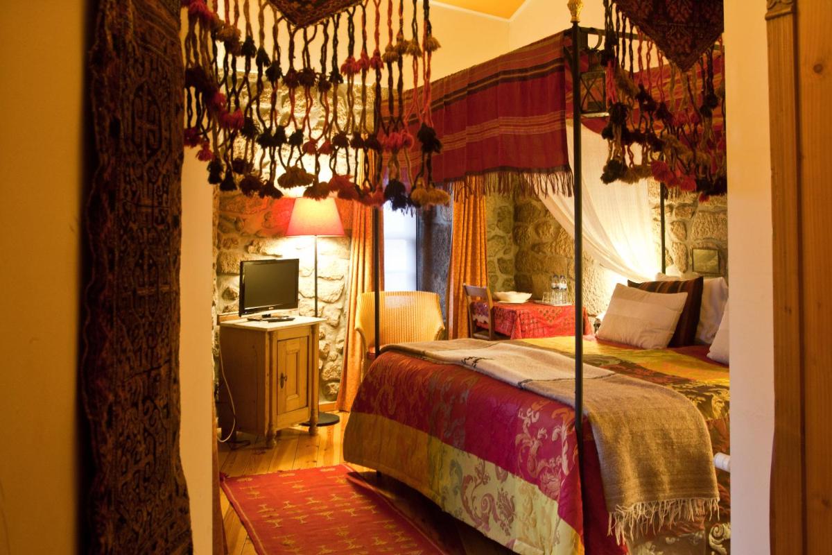 um quarto com uma cama de dossel e uma televisão em Hotel Rural Quinta da Geia em Aldeia das Dez mais 35 fotografias