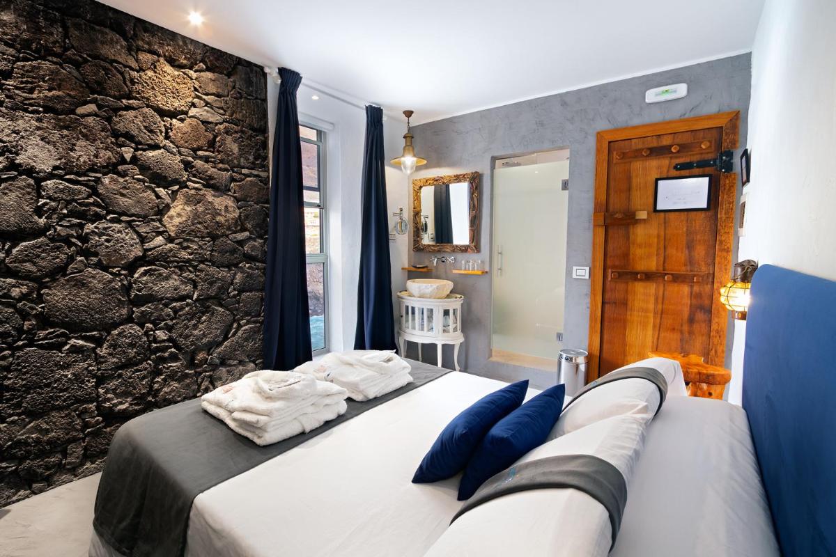 Un dormitorio con una cama y una pared de piedra. en Hotel Puntagrande, en La Frontera