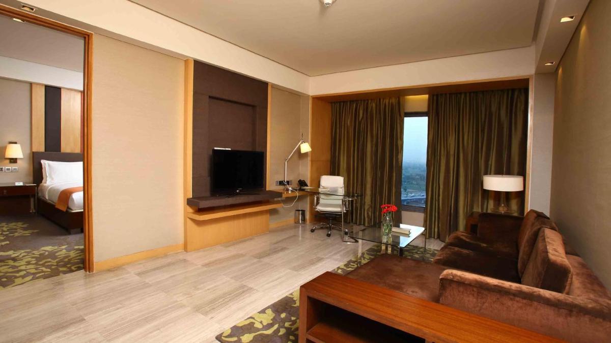 a living room with a couch and a television in a hotel room at Holiday Inn New Delhi Mayur Vihar Noida by IHG in New Delhi a living room with a couch and a television in a hotel room at Holiday Inn New Delhi Mayur Vihar Noida by IHG in New Delhi