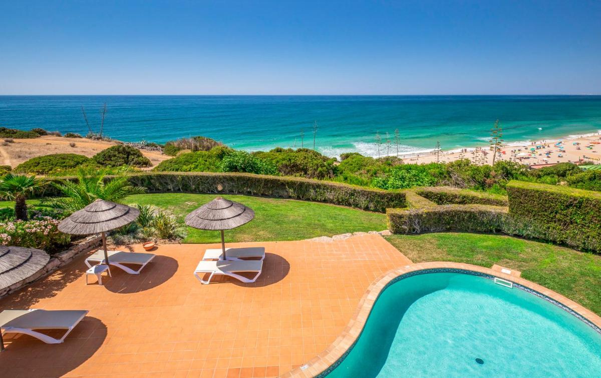 uma piscina com guarda-sóis e cadeiras e a praia em Clube Porto Mos - Sunplace Hotels & Beach Resort em Lagos
