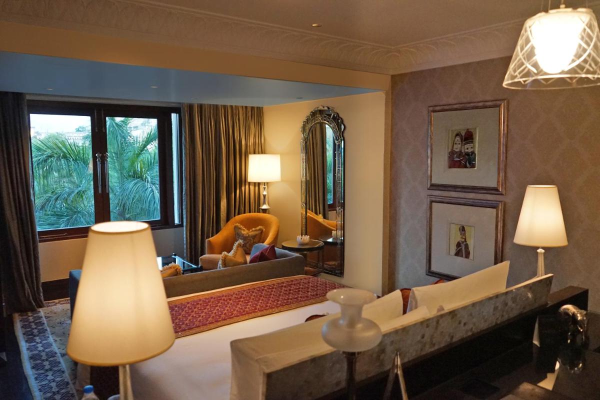 a hotel room with a large bed and a living room at The Leela Palace Udaipur in Udaipur