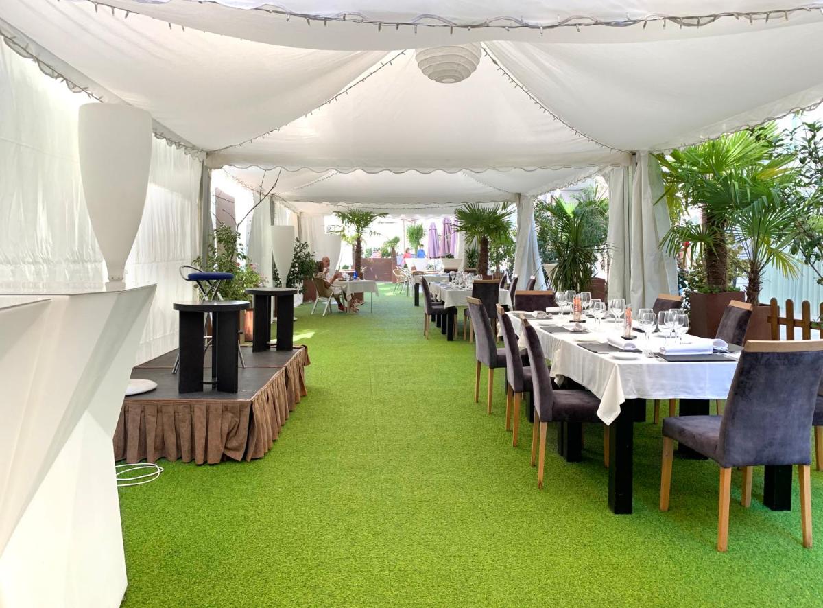 Tienda blanca con mesas y sillas sobre césped verde en Gran Hotel Don Manuel, en Cáceres