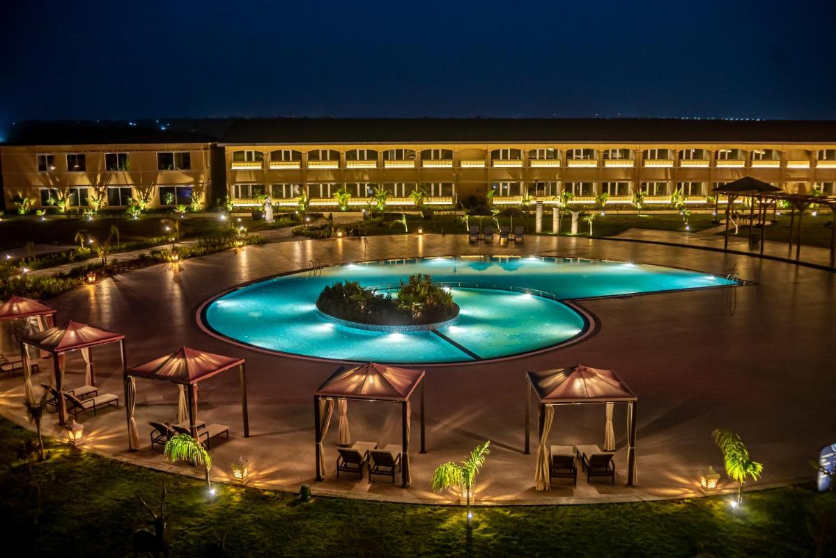 a hotel with a large swimming pool at night at Hawthorn Suites by Wyndham Dwarka in Dwarka a hotel with a large swimming pool at night at Hawthorn Suites by Wyndham Dwarka in Dwarka