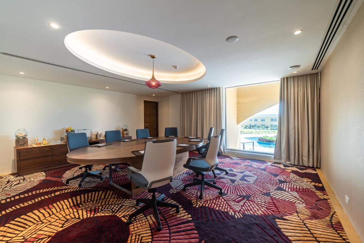 a conference room with a table and chairs on a rug at Hawthorn Suites by Wyndham Dwarka in Dwarka a conference room with a table and chairs on a rug at Hawthorn Suites by Wyndham Dwarka in Dwarka