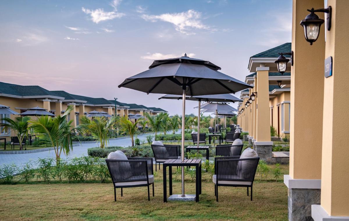 a group of chairs and tables with an umbrella at Hawthorn Suites by Wyndham Dwarka in Dwarka a group of chairs and tables with an umbrella at Hawthorn Suites by Wyndham Dwarka in Dwarka