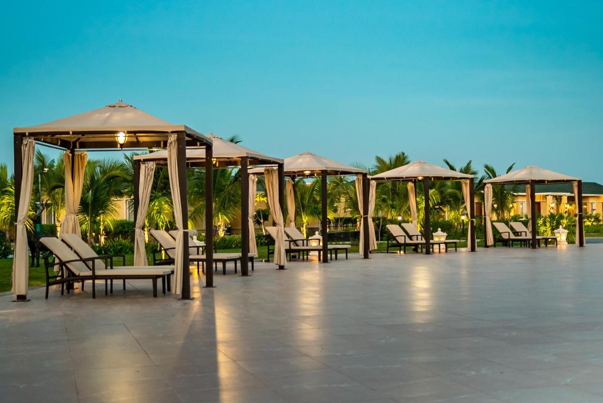a patio with tables and chairs and umbrellas at Hawthorn Suites by Wyndham Dwarka in Dwarka a patio with tables and chairs and umbrellas at Hawthorn Suites by Wyndham Dwarka in Dwarka