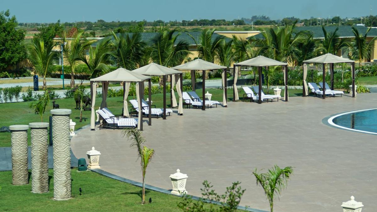 a resort with a pool and chairs and umbrellas at Hawthorn Suites by Wyndham Dwarka in Dwarka a resort with a pool and chairs and umbrellas at Hawthorn Suites by Wyndham Dwarka in Dwarka