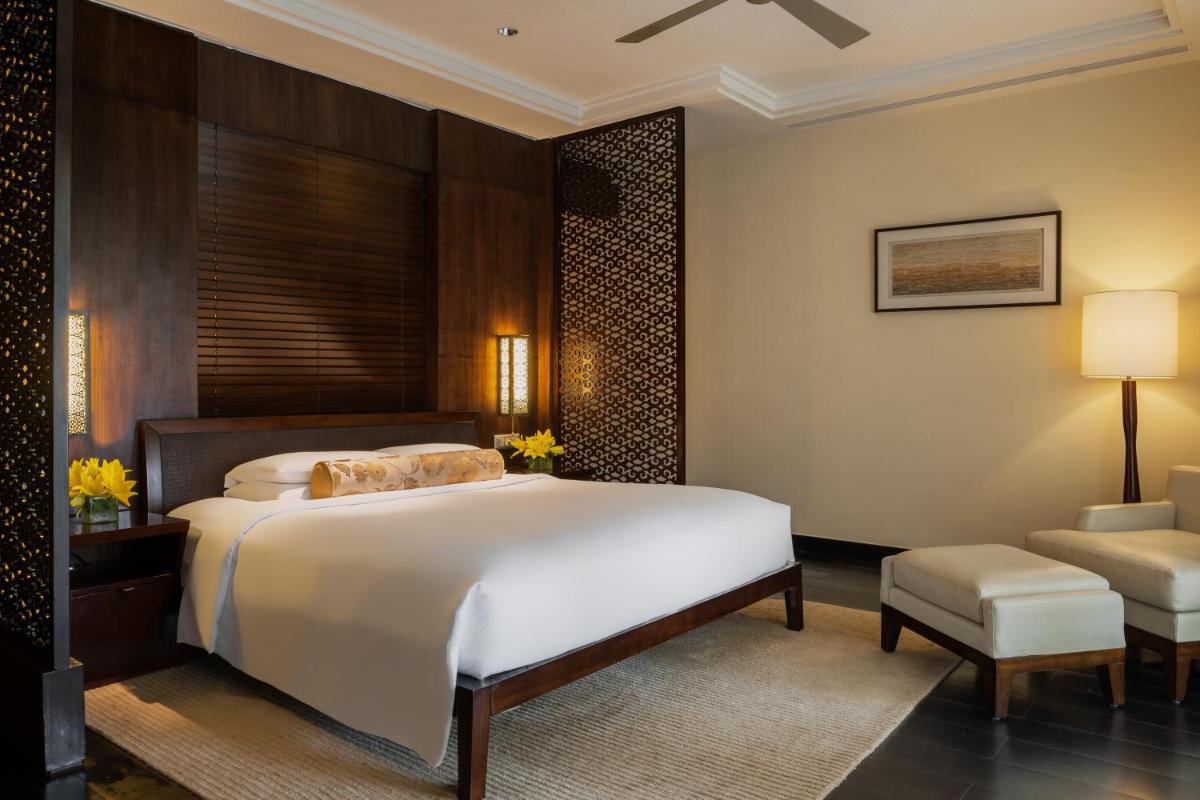 a bedroom with a large bed and a chair at Grand Hyatt Goa in Panaji a bedroom with a large bed and a chair at Grand Hyatt Goa in Panaji