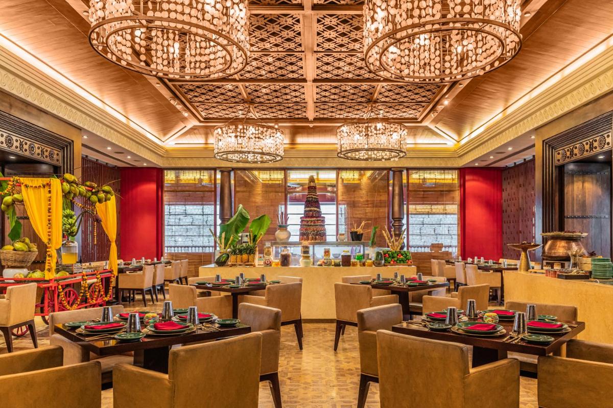 a restaurant with tables and chairs and chandeliers at Grand Hyatt Goa in Panaji a restaurant with tables and chairs and chandeliers at Grand Hyatt Goa in Panaji