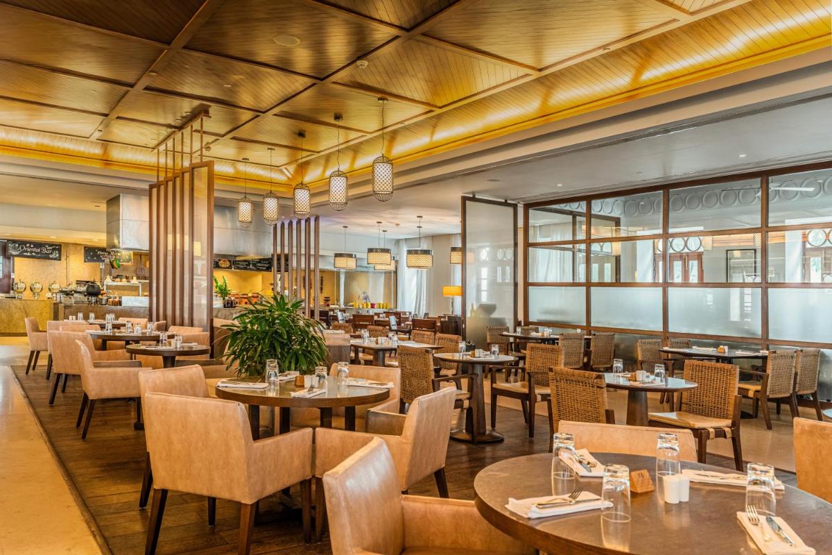 a dining room with tables and chairs and a restaurant at Grand Hyatt Goa in Panaji a dining room with tables and chairs and a restaurant at Grand Hyatt Goa in Panaji