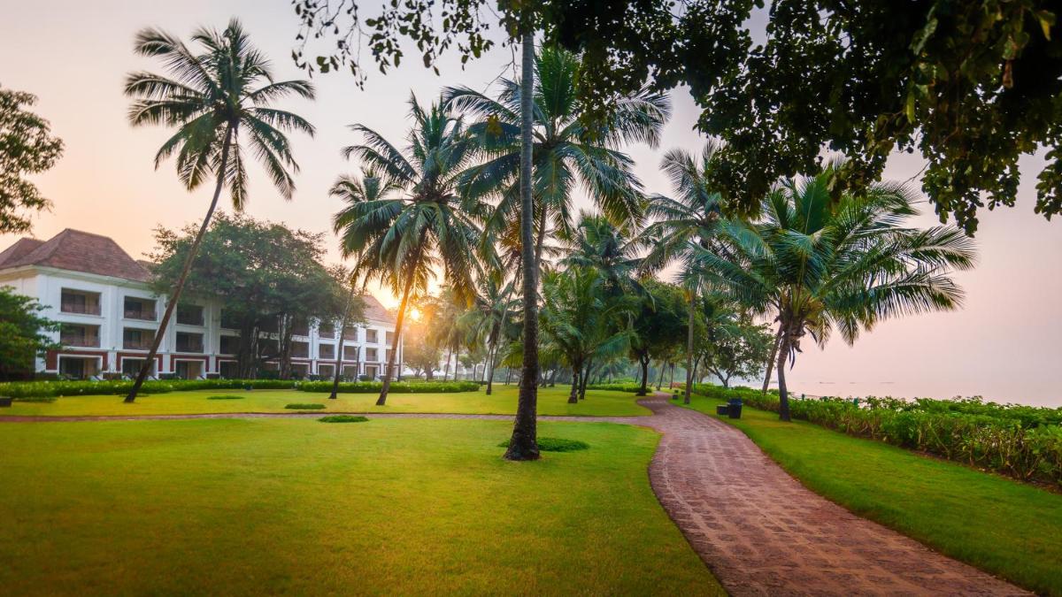 a park with palm trees in front of a building at Grand Hyatt Goa in Panaji a park with palm trees in front of a building at Grand Hyatt Goa in Panaji
