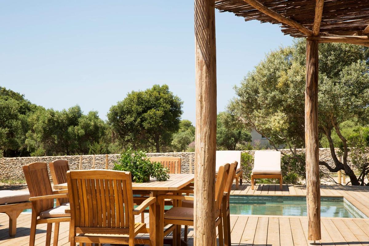 une table et des chaises en bois à côté d'une piscine dans l'établissement U Capu Biancu, à Bonifacio