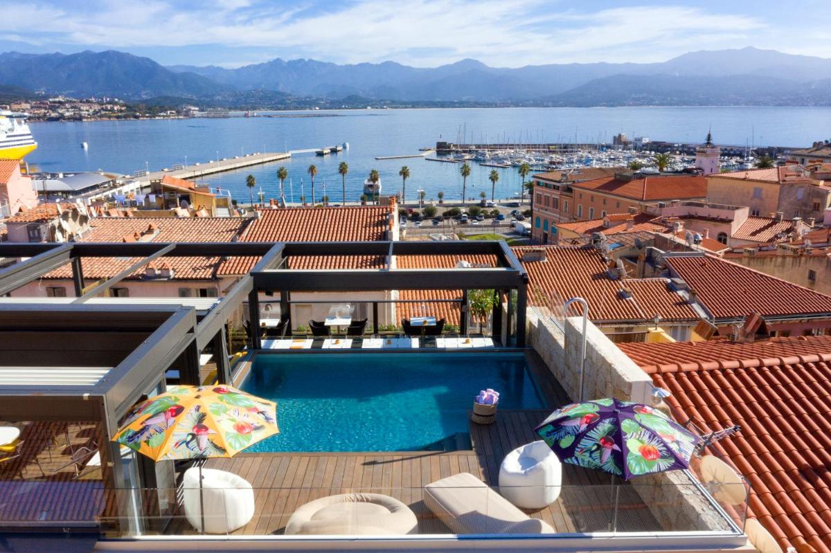 une piscine avec parasols et vue sur l'eau dans l'établissement Hôtel Fesch & Spa, à Ajaccio