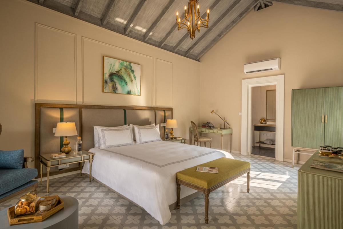 a bedroom with a large white bed and a couch at MansionHaus in Anjuna