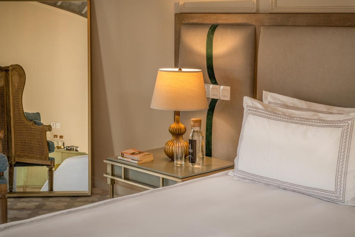 a bedroom with a bed with a lamp and a side table at MansionHaus in Anjuna