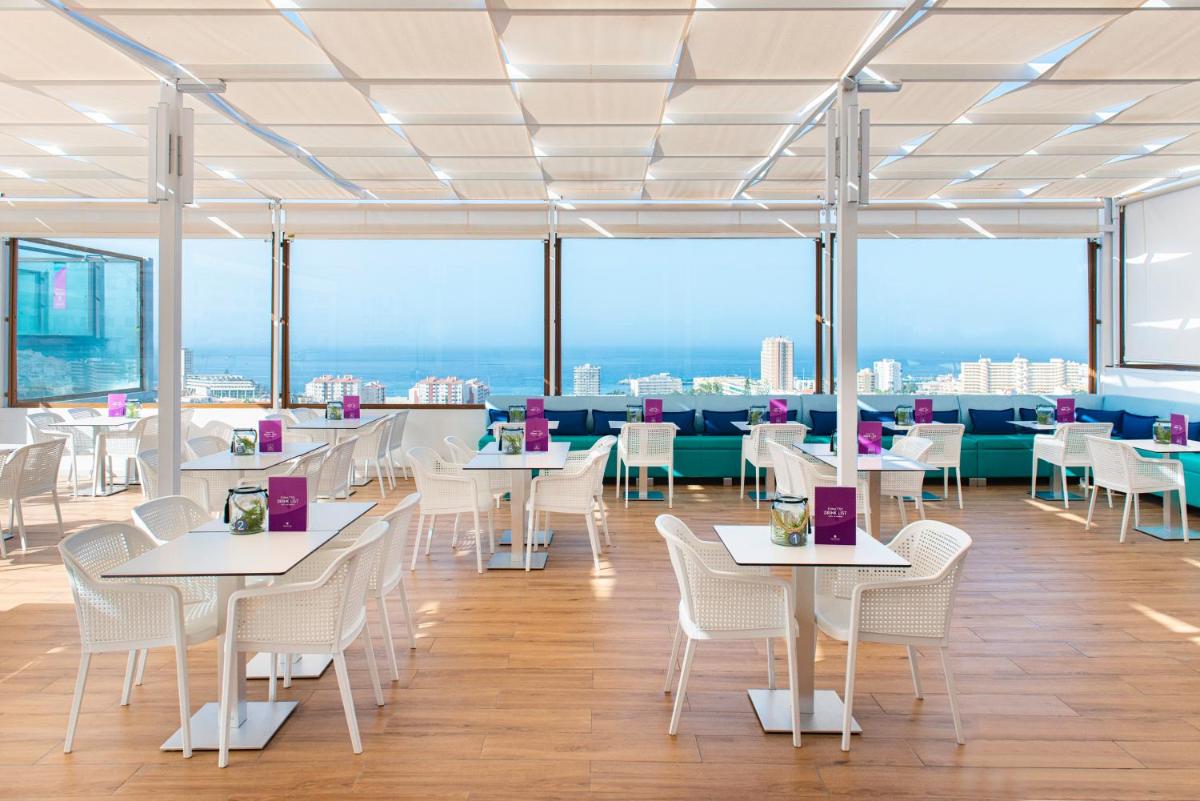 Un restaurante con mesas y sillas blancas con vistas. en Paradise Park Fun Lifestyle Hotel, en Los Cristianos