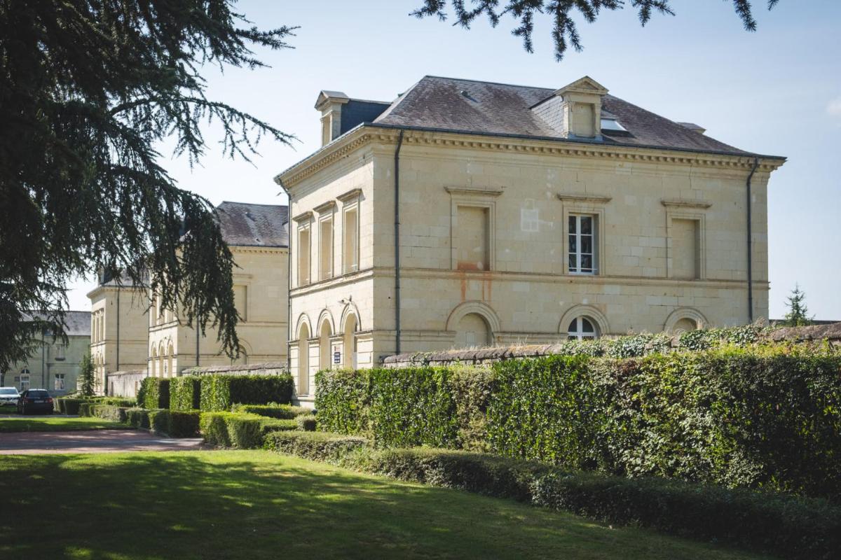 - un grand bâtiment en pierre avec des buissons en face dans l'établissement Domaine de Roiffé, à Roiffé
