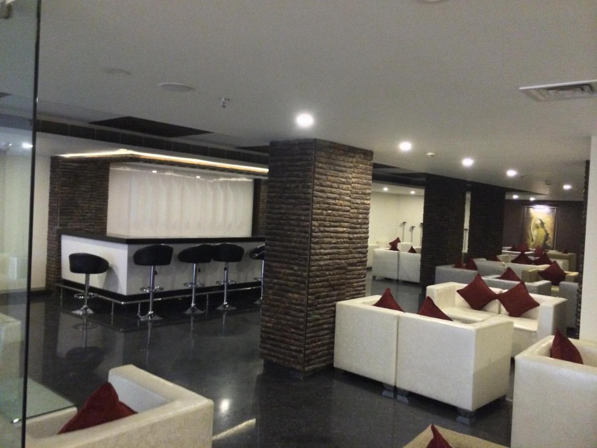 a lobby with white couches and chairs and a bar at Golden Tulip Jaipur in Jaipur