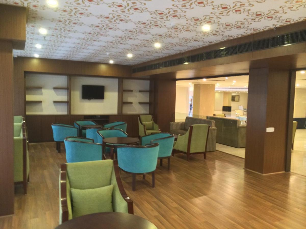 a restaurant with blue chairs and tables and a kitchen at Golden Tulip Jaipur in Jaipur