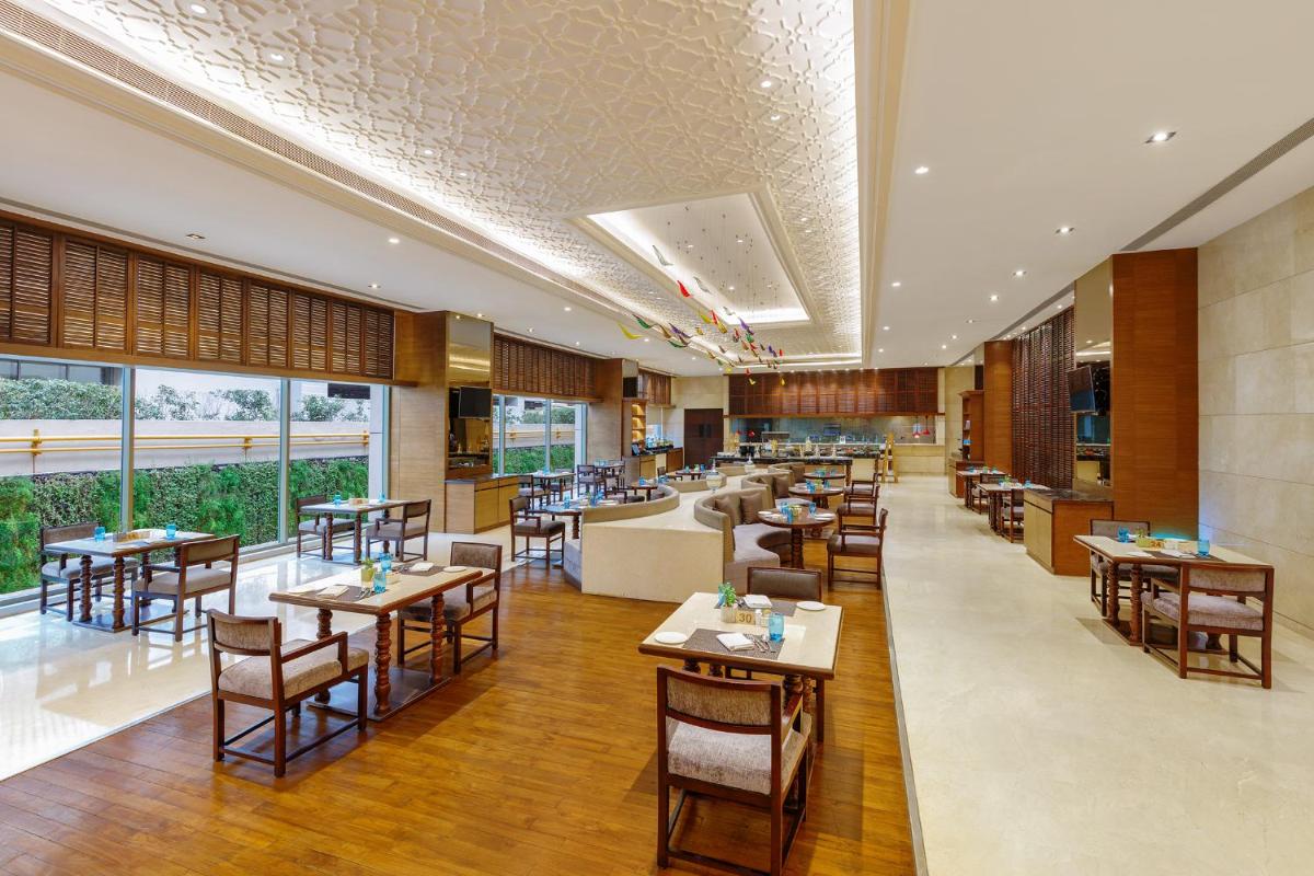 a restaurant with tables and chairs and a couch at Pride Plaza Hotel, Aerocity New Delhi in New Delhi a restaurant with tables and chairs and a couch at Pride Plaza Hotel, Aerocity New Delhi in New Delhi