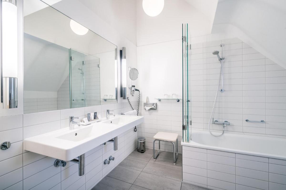 ein weißes Badezimmer mit Waschbecken und Dusche in der Unterkunft Deidesheimer Hof in Deidesheim