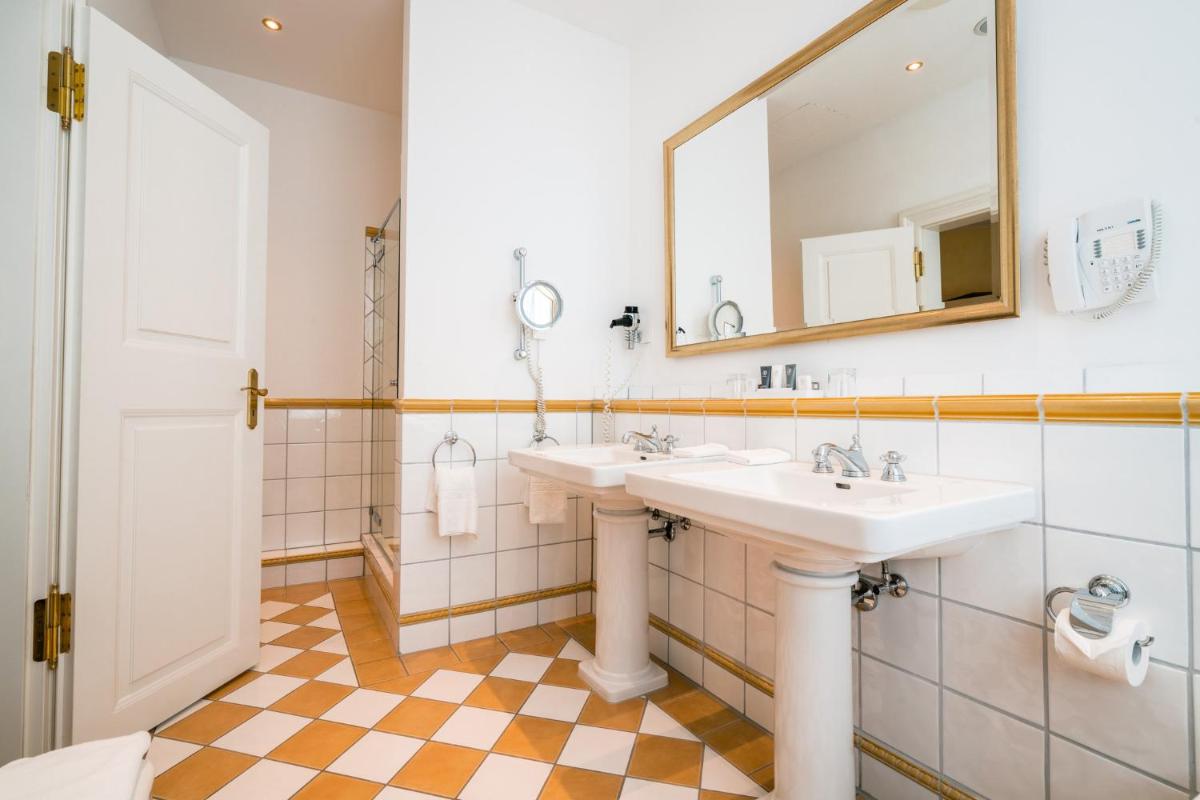 ein Badezimmer mit zwei Waschbecken und einem Spiegel in der Unterkunft Deidesheimer Hof in Deidesheim