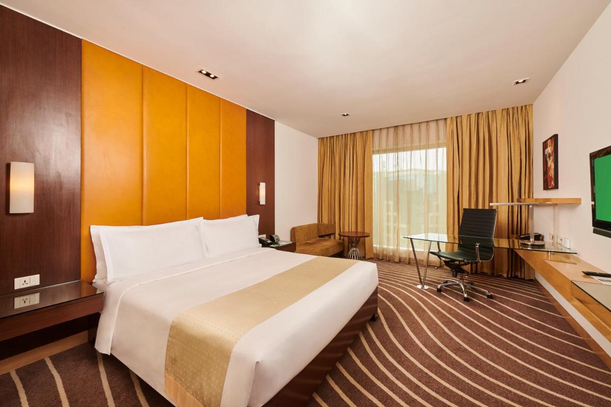 a hotel room with a large bed and a desk at Holiday Inn Mumbai International Airport by IHG in Mumbai