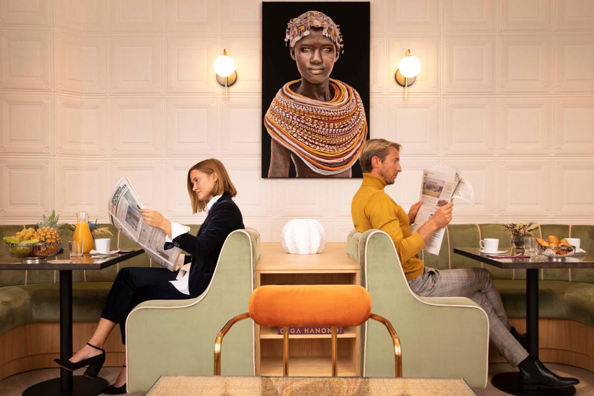 un homme et une femme assis à une table dans un restaurant dans l'établissement Hotel Phileas Lazare & Spa - Opera, à Paris
