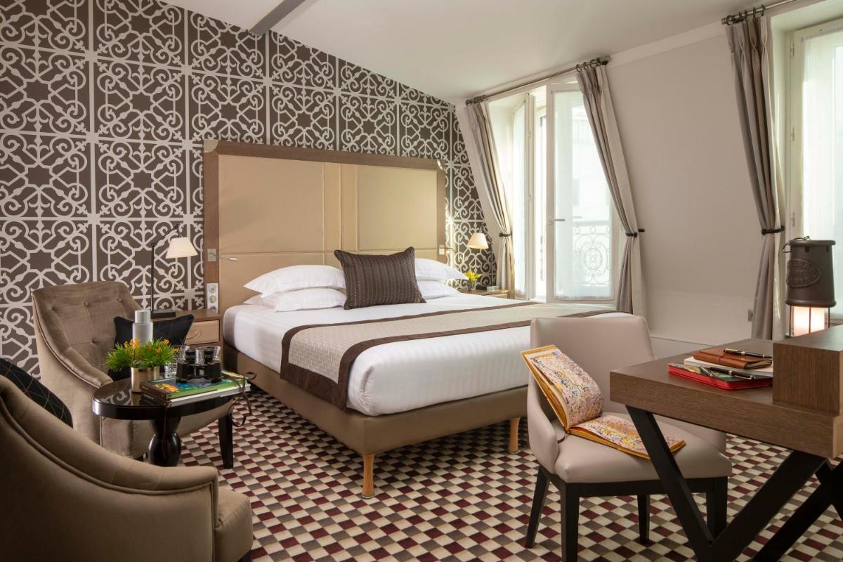 une chambre d'hôtel avec un lit, une table et des chaises dans l'établissement Hotel Phileas Lazare & Spa - Opera, à Paris
