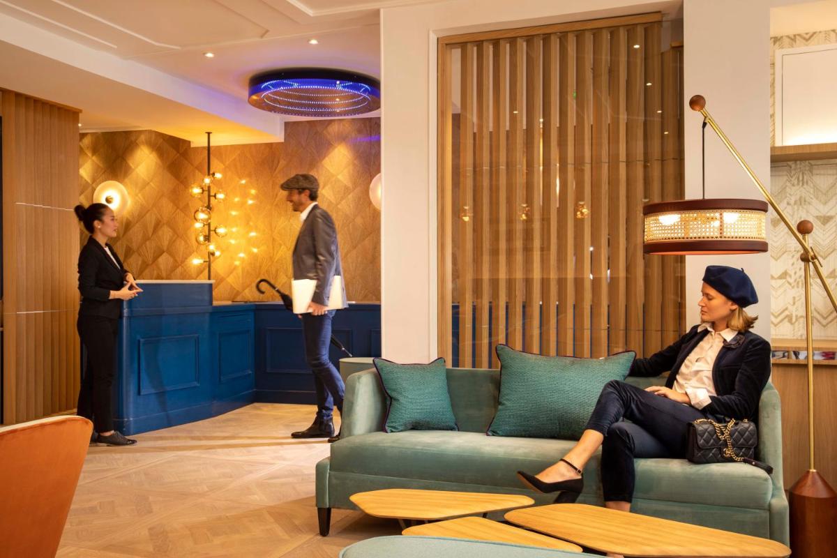 une femme assise sur un canapé dans le hall dans l'établissement Hotel Phileas Lazare & Spa - Opera, à Paris