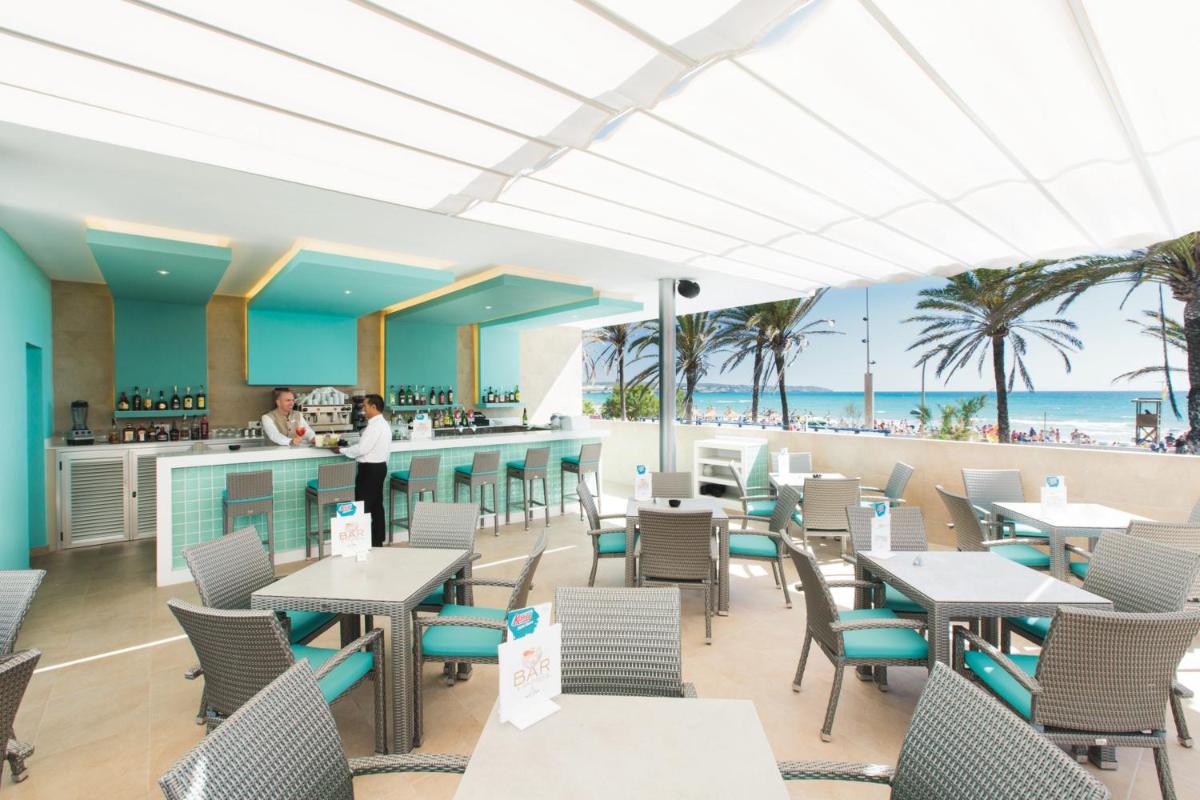 Un restaurante con mesas y sillas y la playa. en Hotel Riu San Francisco - Adults Only, en Playa de Palma