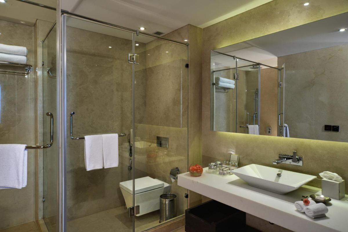 a bathroom with a glass shower and a sink at Pride Plaza Hotel, Kolkata in Kolkata