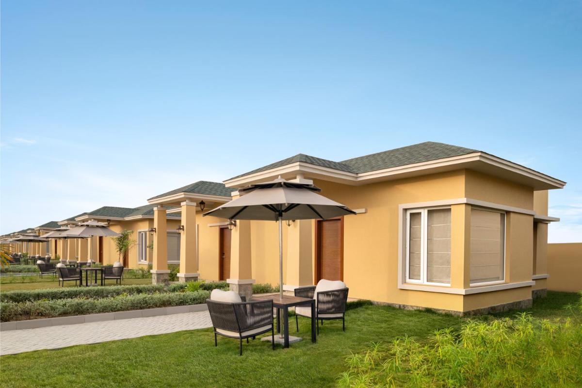 a house with a table and chairs and an umbrella at Hawthorn Suites by Wyndham Dwarka in Dwarka a house with a table and chairs and an umbrella at Hawthorn Suites by Wyndham Dwarka in Dwarka