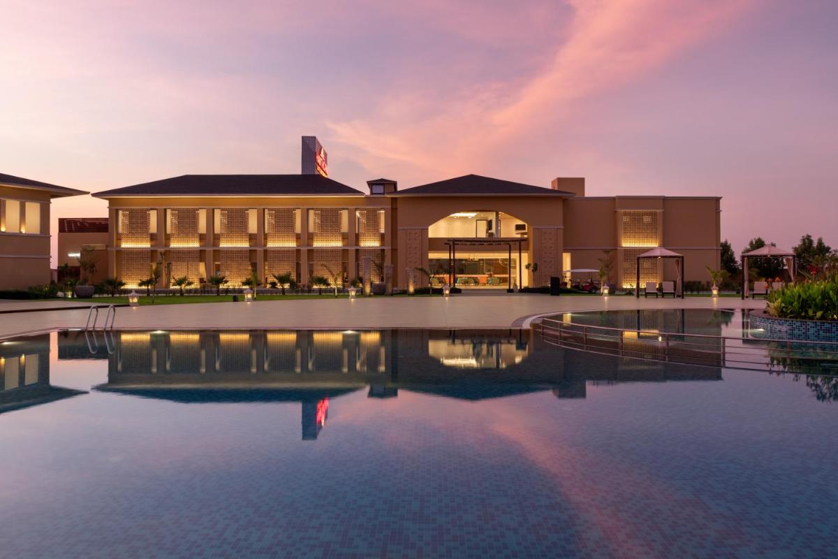 a building with a pool in front of it at Hawthorn Suites by Wyndham Dwarka in Dwarka a building with a pool in front of it at Hawthorn Suites by Wyndham Dwarka in Dwarka