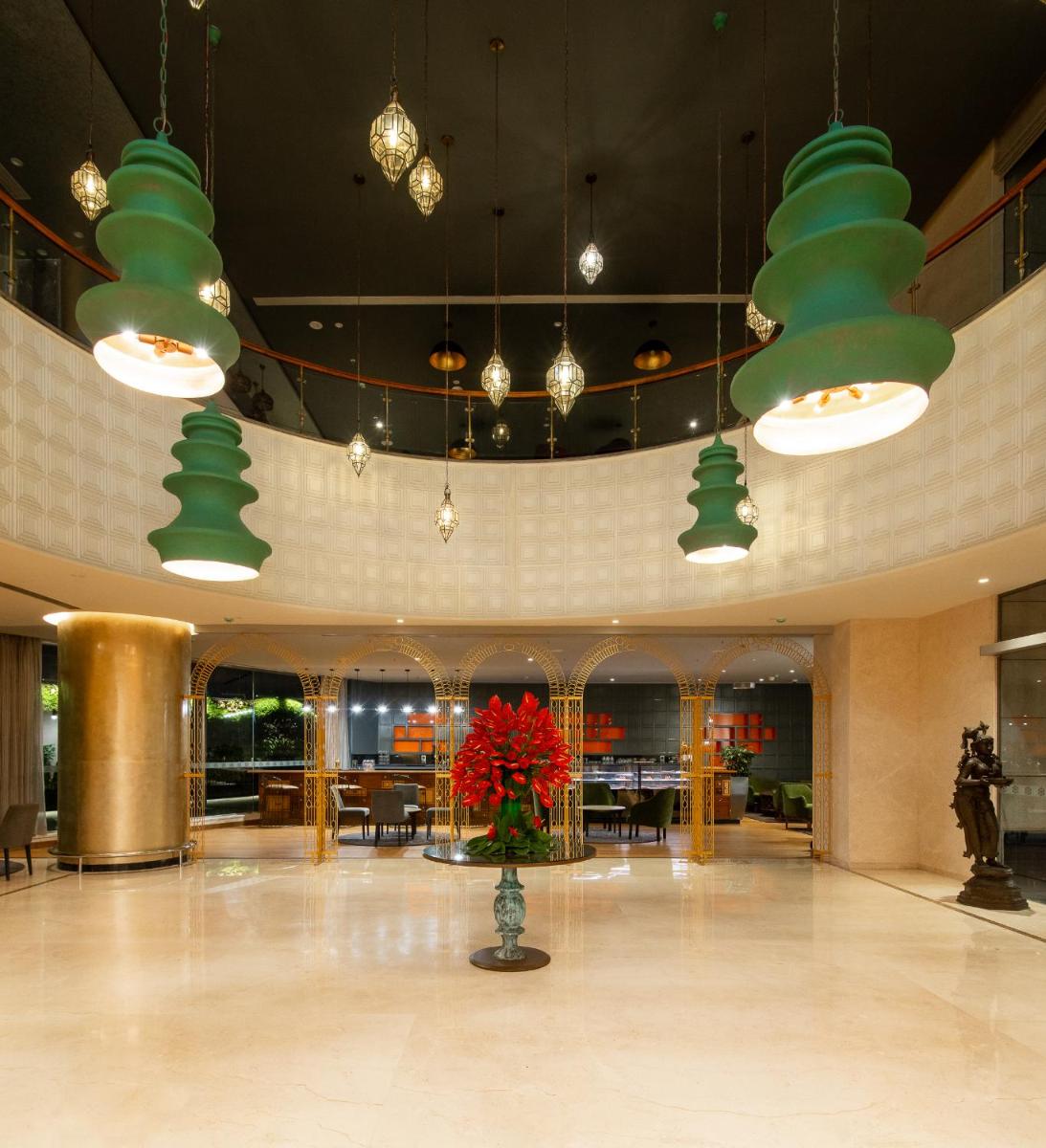 a lobby with green pendant lights and a vase with red flowers at Grand Mercure Bengaluru at Gopalan Mall - An Accor Brand in Bengaluru a lobby with green pendant lights and a vase with red flowers at Grand Mercure Bengaluru at Gopalan Mall - An Accor Brand in Bengaluru