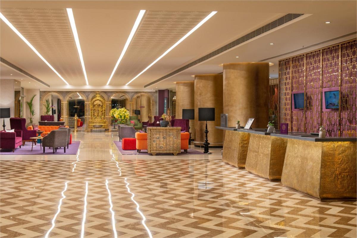 a lobby of a hotel with chairs and tables at Grand Mercure Bengaluru at Gopalan Mall - An Accor Brand in Bengaluru a lobby of a hotel with chairs and tables at Grand Mercure Bengaluru at Gopalan Mall - An Accor Brand in Bengaluru