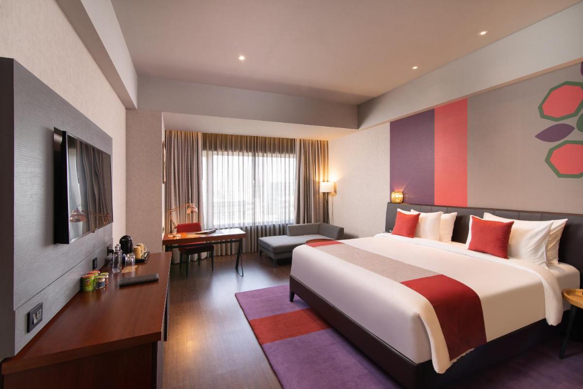 a hotel room with a large bed and a desk at Grand Mercure Bengaluru at Gopalan Mall - An Accor Brand in Bengaluru a hotel room with a large bed and a desk at Grand Mercure Bengaluru at Gopalan Mall - An Accor Brand in Bengaluru