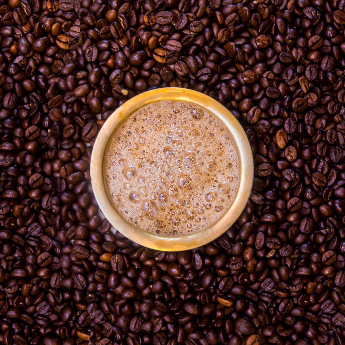 a cup of coffee sitting on a pile of coffee beans at Grand Mercure Bengaluru at Gopalan Mall - An Accor Brand in Bengaluru a cup of coffee sitting on a pile of coffee beans at Grand Mercure Bengaluru at Gopalan Mall - An Accor Brand in Bengaluru