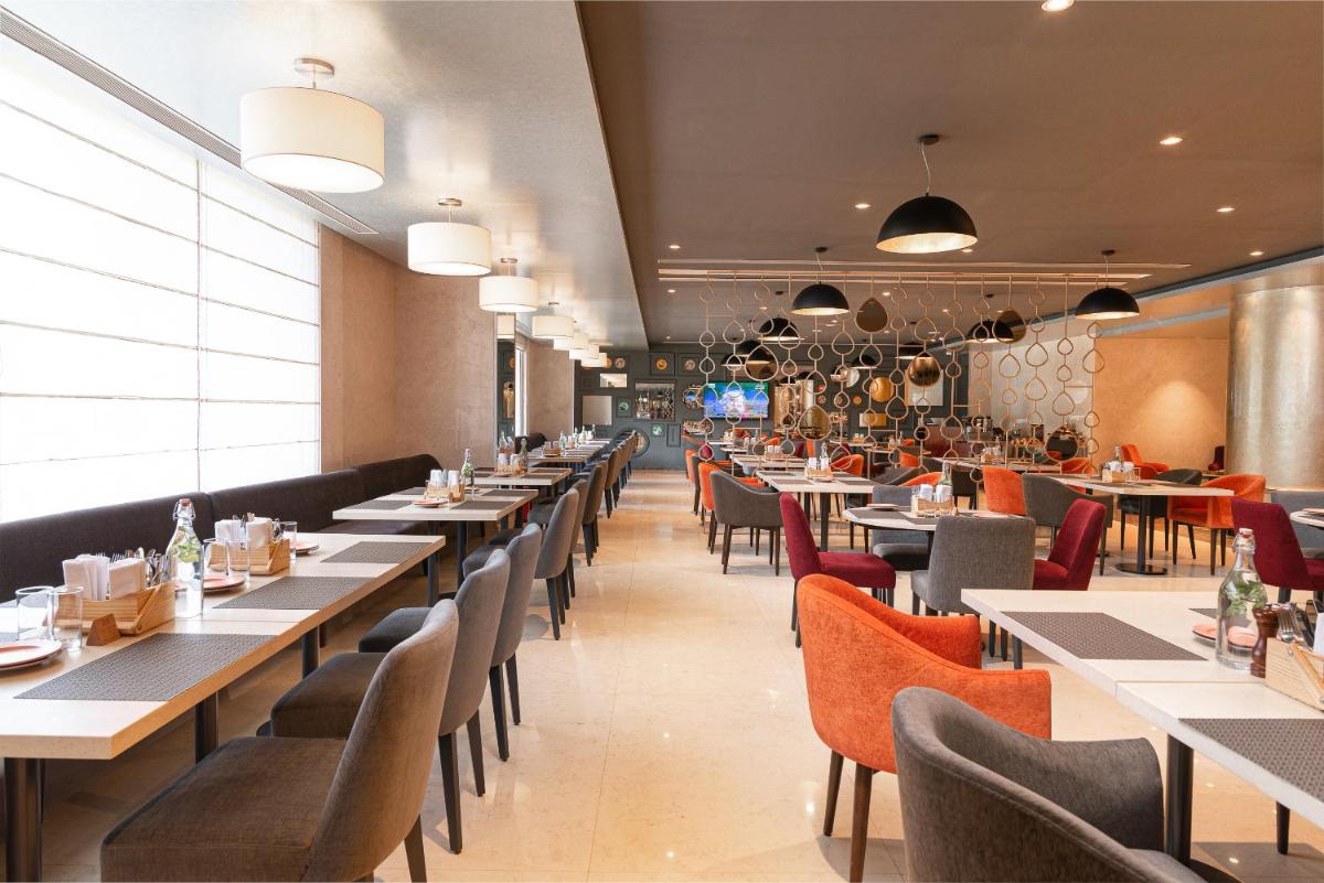 a dining room with long tables and chairs at Grand Mercure Bengaluru at Gopalan Mall - An Accor Brand in Bengaluru a dining room with long tables and chairs at Grand Mercure Bengaluru at Gopalan Mall - An Accor Brand in Bengaluru