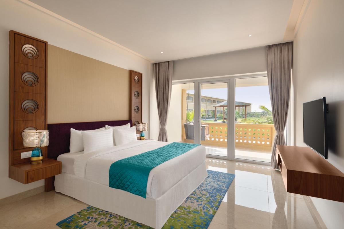 a hotel room with a bed and a television at Hawthorn Suites by Wyndham Dwarka in Dwarka a hotel room with a bed and a television at Hawthorn Suites by Wyndham Dwarka in Dwarka