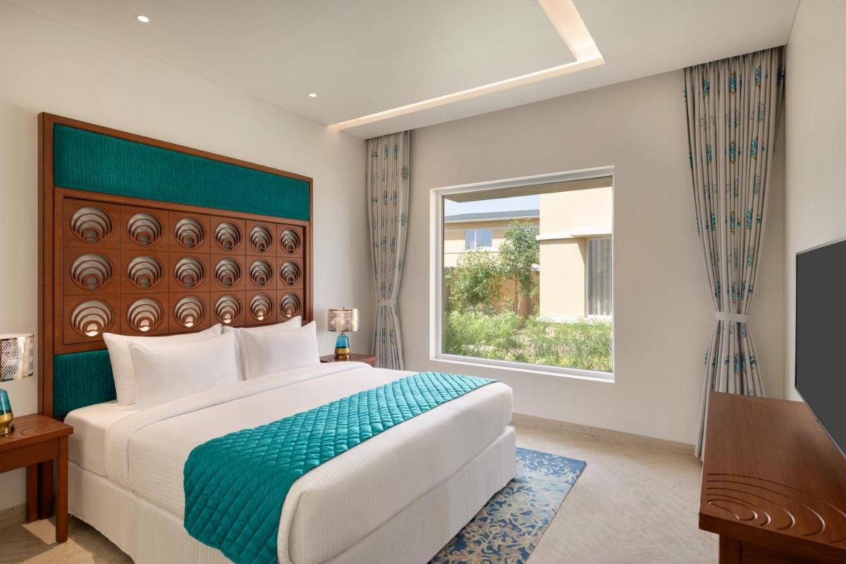 a bedroom with a large bed and a window at Hawthorn Suites by Wyndham Dwarka in Dwarka a bedroom with a large bed and a window at Hawthorn Suites by Wyndham Dwarka in Dwarka