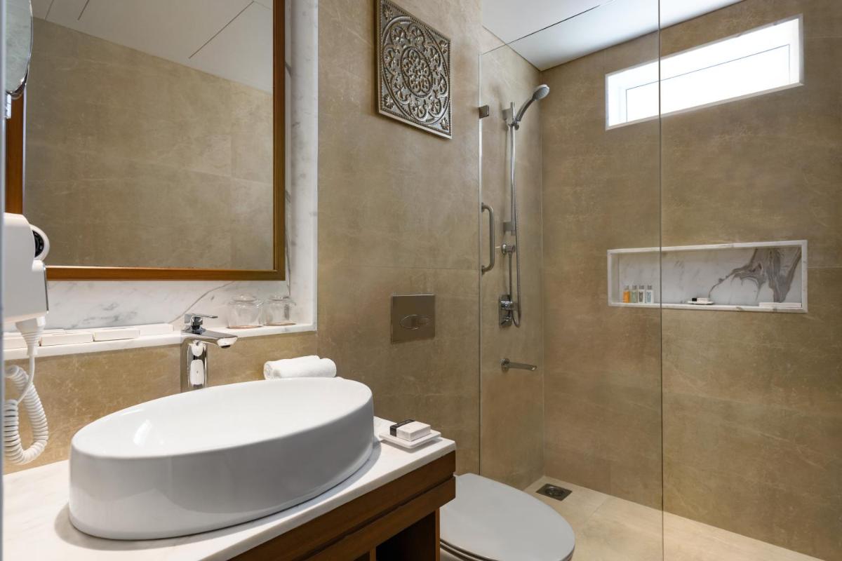 a bathroom with a shower and a toilet and a sink at Hawthorn Suites by Wyndham Dwarka in Dwarka a bathroom with a shower and a toilet and a sink at Hawthorn Suites by Wyndham Dwarka in Dwarka
