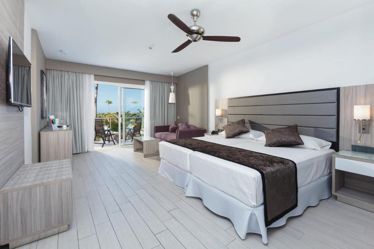 Un dormitorio con una cama grande con ventilador de techo. en Hotel Riu Palace Tenerife, en Adeje