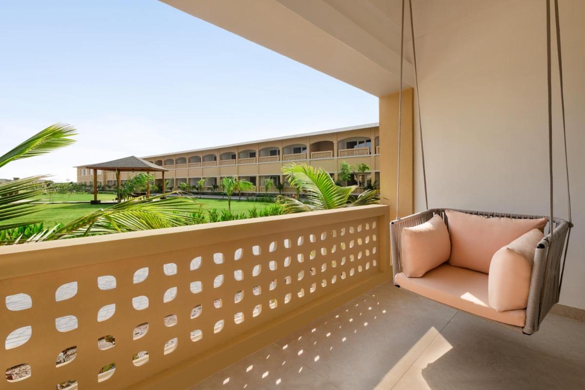 a balcony with a chair and a view of a building at Hawthorn Suites by Wyndham Dwarka in Dwarka a balcony with a chair and a view of a building at Hawthorn Suites by Wyndham Dwarka in Dwarka